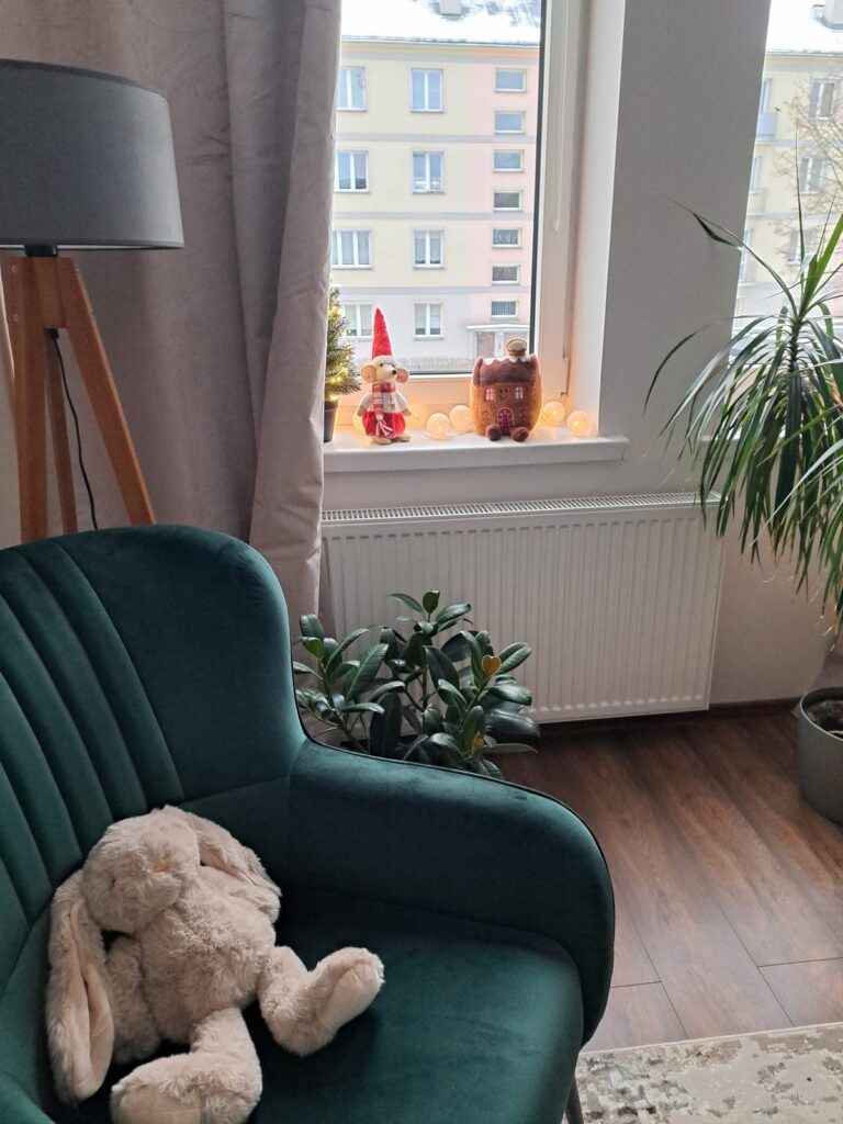 Zielony fotel z pluszowym misiem przy oknie