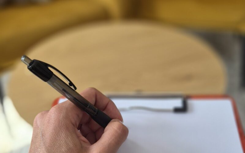 Dłoń zapisująca notatki na kartce podczas konsultacji